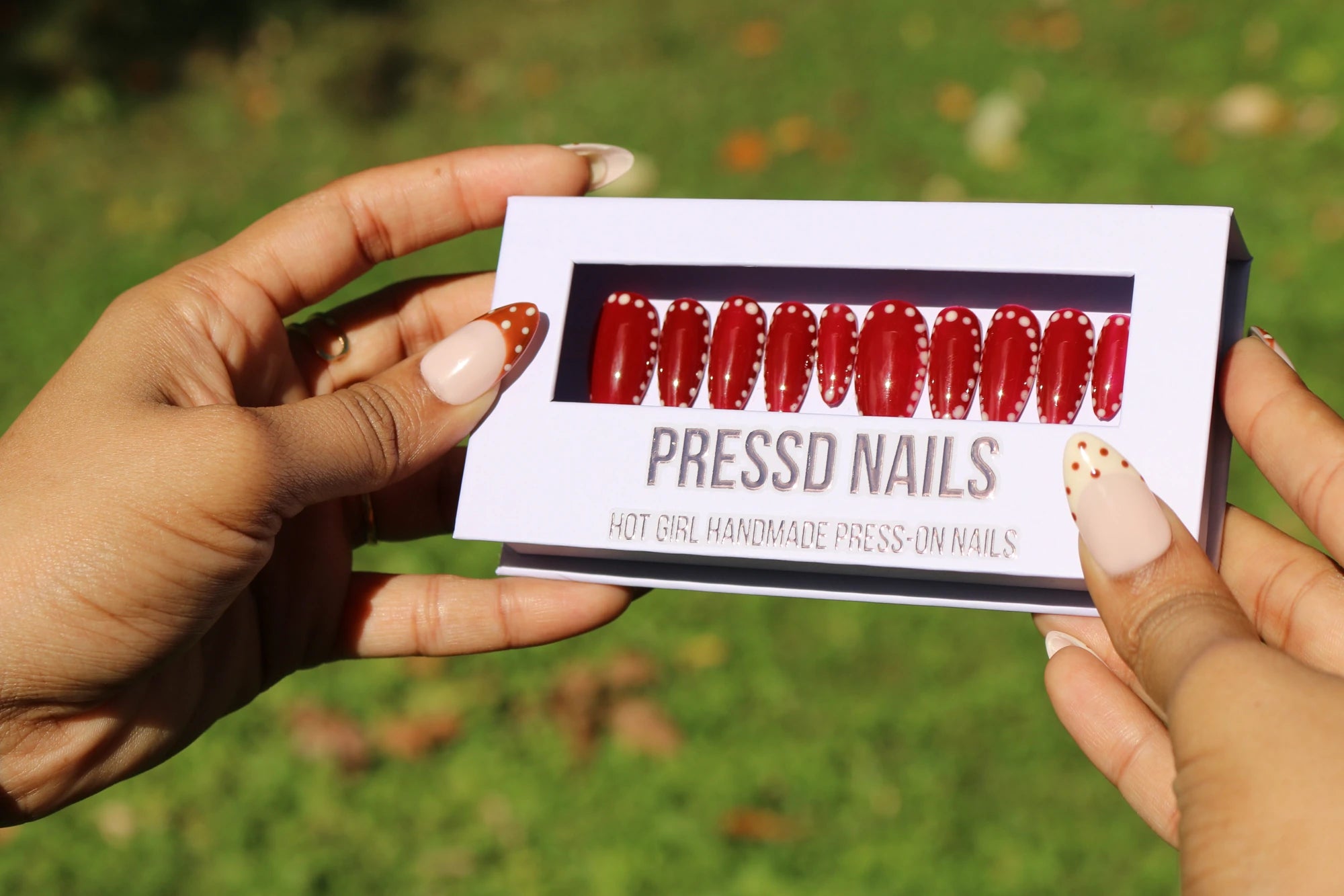 Burgundy Dots press-on nail set shown in its Pressd Nails box outdoors