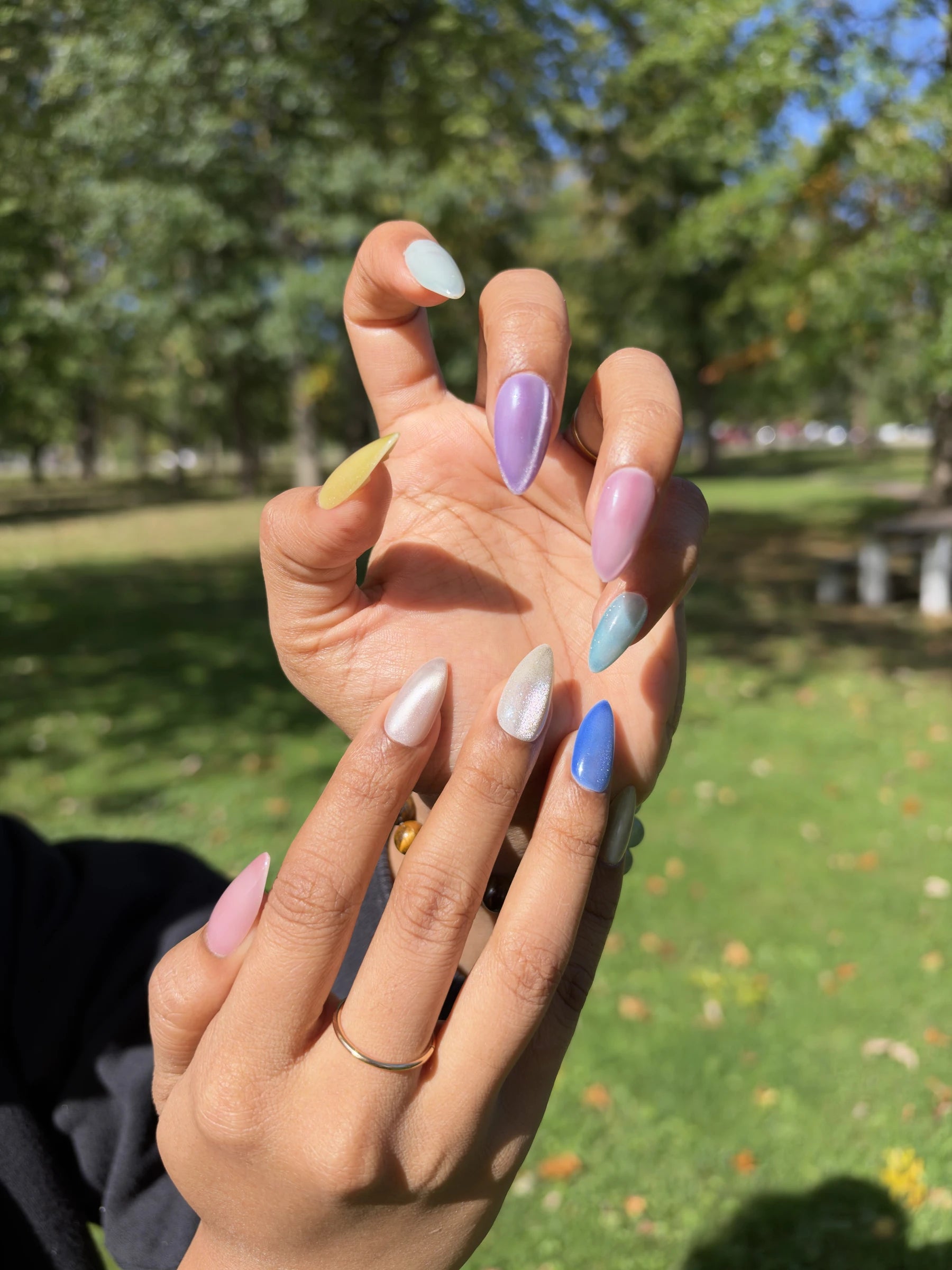 Pastel press-on nails in lavender, pink, blue, yellow and pearl worn outdoors